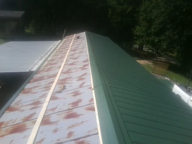 Old rusted panels beside newly installed green metal roofing — Wind Damage Roof Repair by Roofing Brothers in Rotterdam Junction