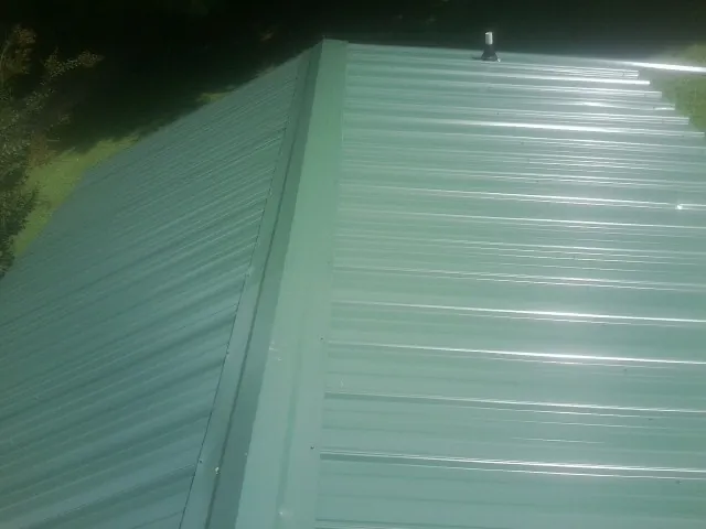 New green metal panels meeting at the ridge of a roof — Flat Roof Repair work by our crew in Rotterdam Junction