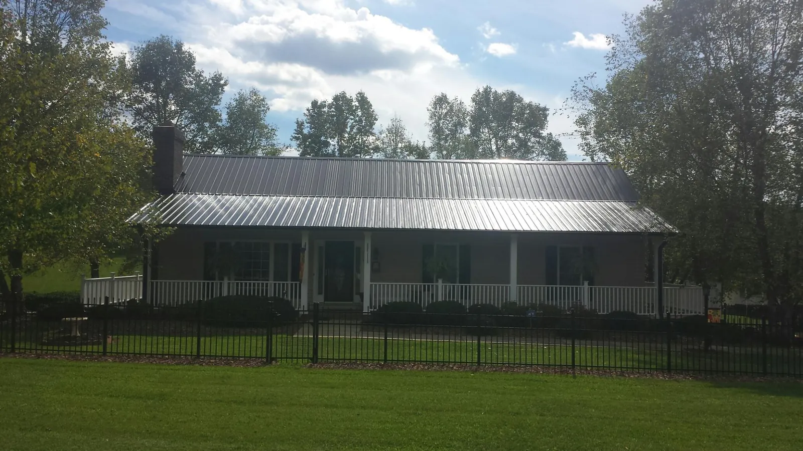 Gray metal roof on a brick ranch with a full width front porch — Gutter Guard Installation work by our crew in Rotterdam Junction