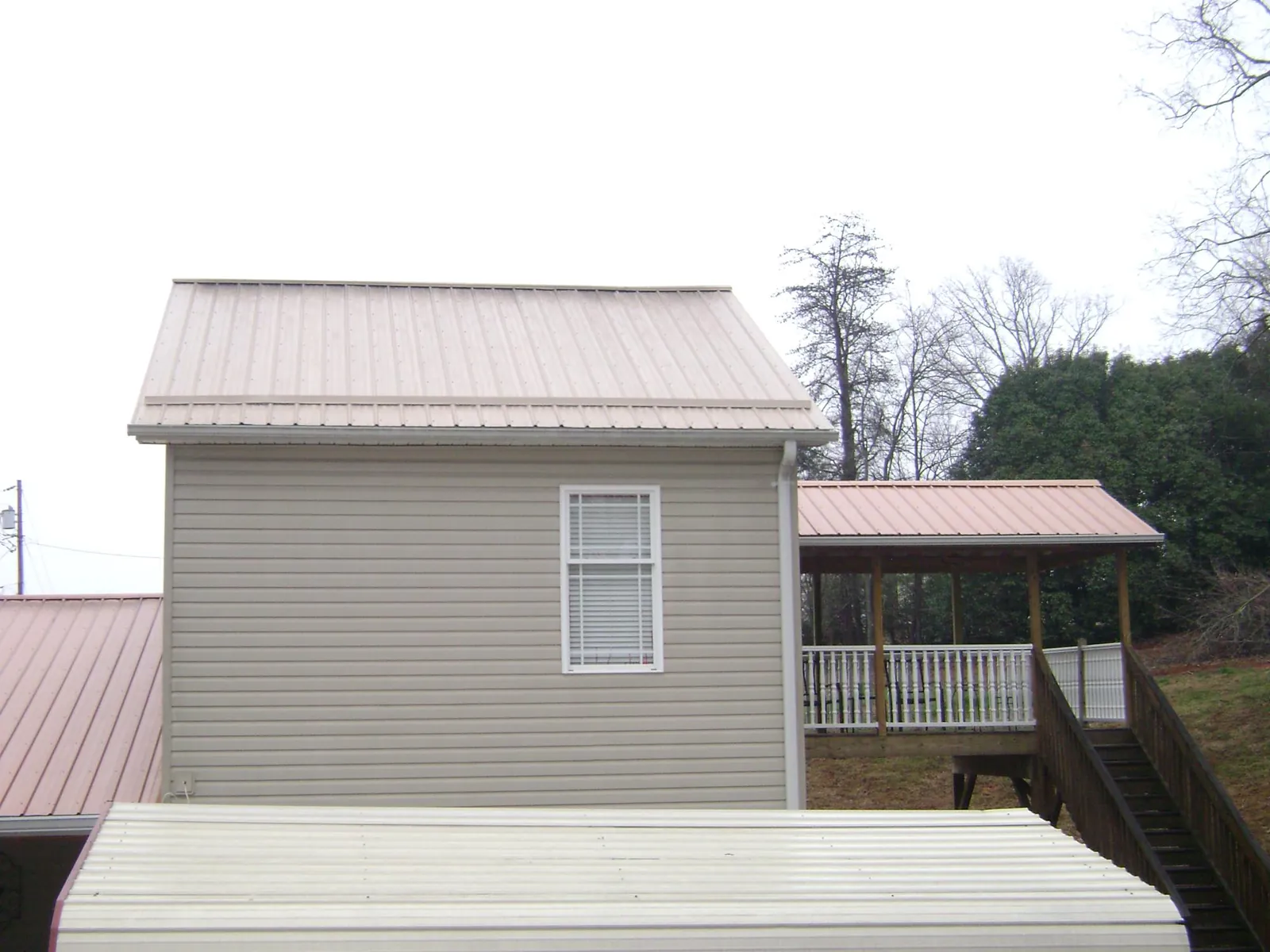 Tan metal roofs on a two story addition and attached porch, from a Roof Replacement job in Rotterdam Junction