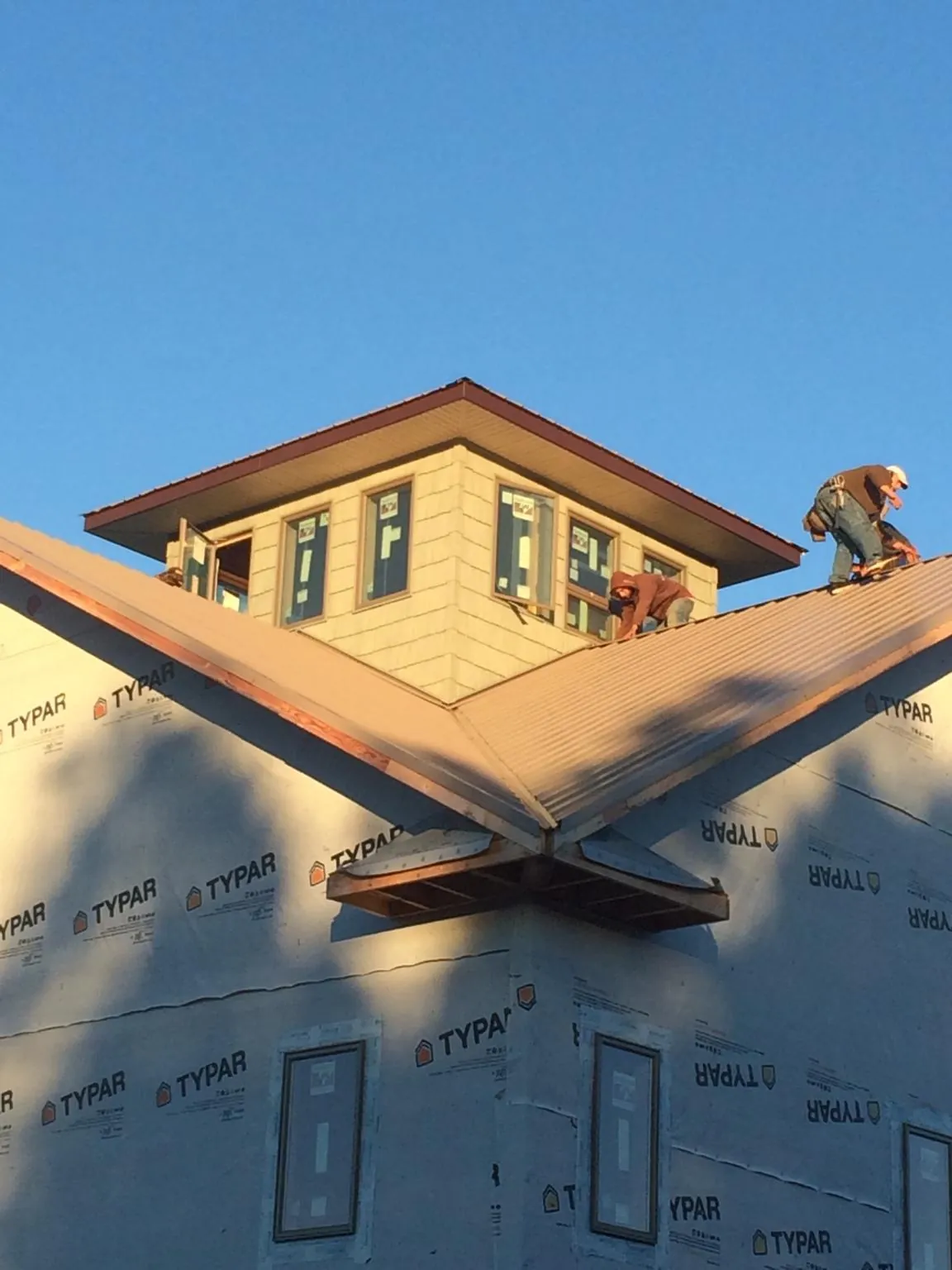 Roofers working around a rooftop cupola on a new metal roof at sunset — Roof Waterproofing in Rotterdam Junction by Roofing Brothers